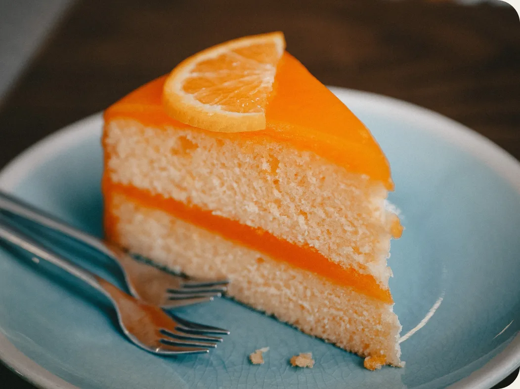 A slice of orange layer cake on a blue plate